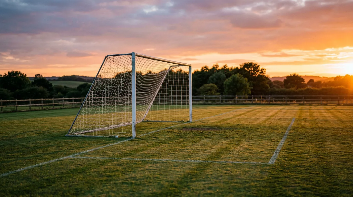 Dos porterías de fútbol enfrentadas en un campo de entrenamiento al atardecer